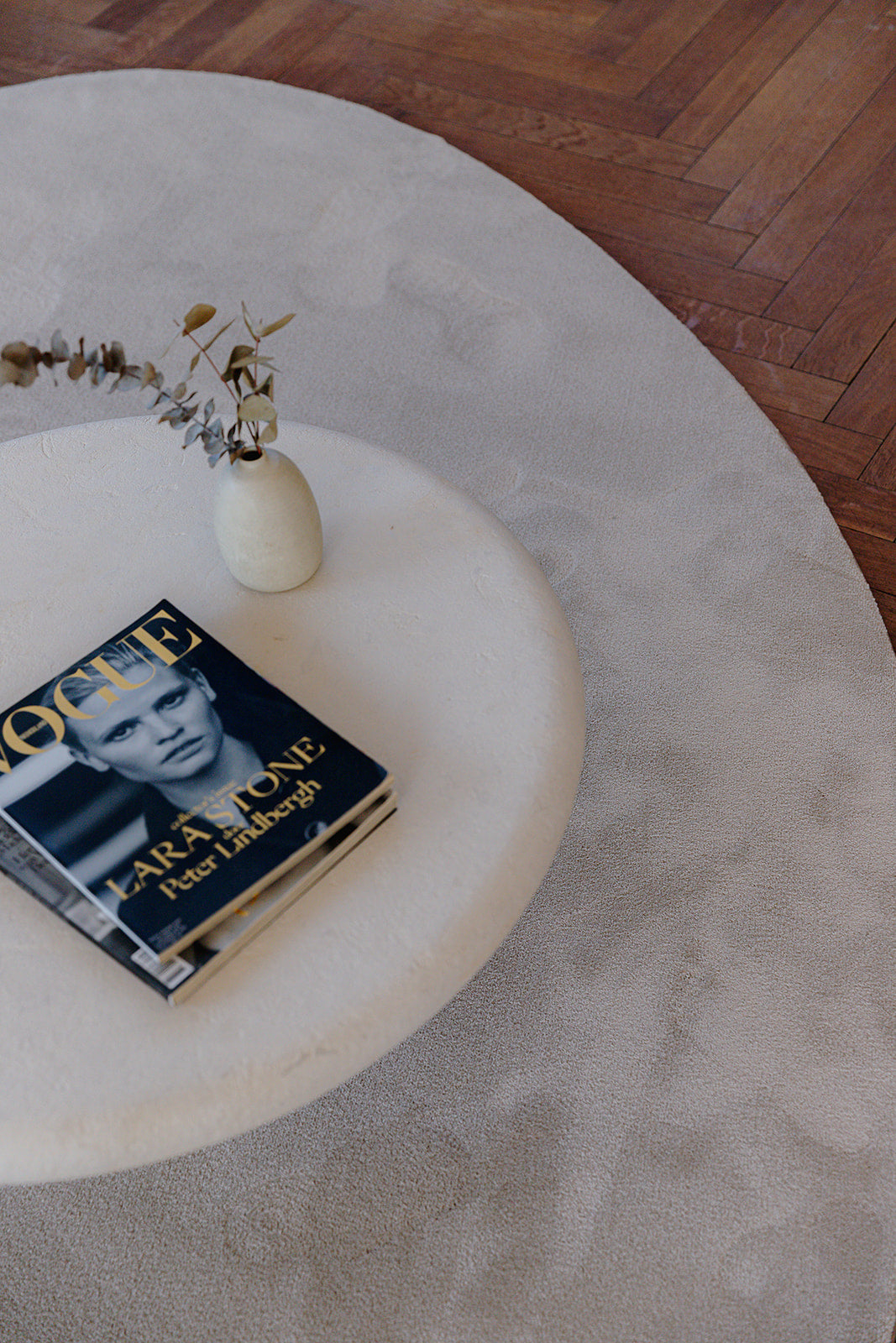 Huiselijk interieur met organische vorm tapijt op houten vloer met bijzettafel en magazine.