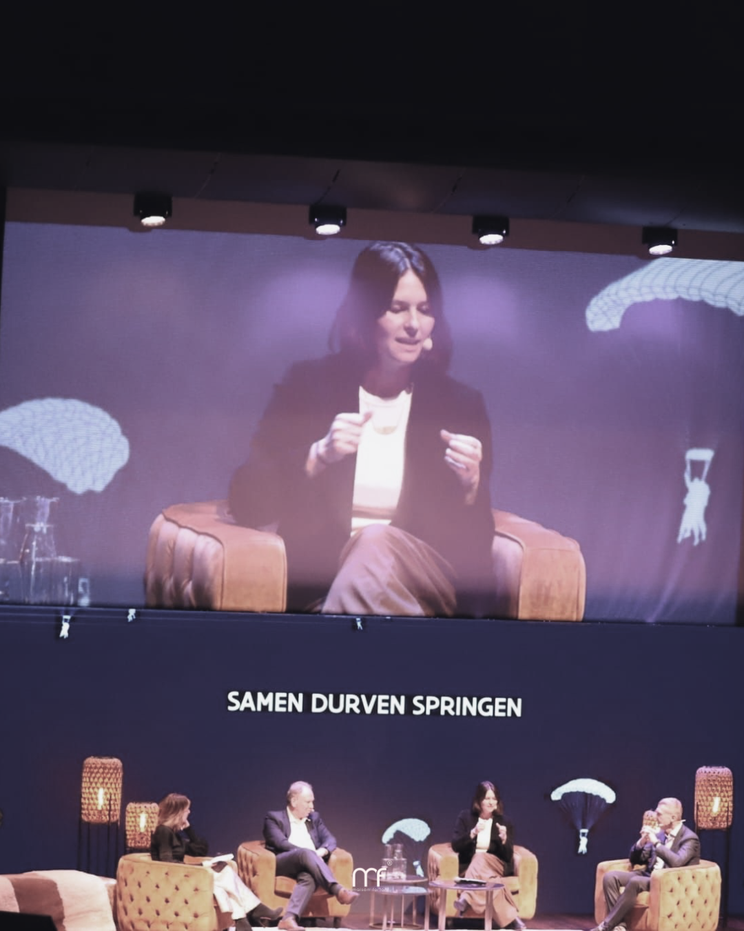 ozefien op het podium als spreker tijdens het VLAIO Nieuwjaarsevent 2026, in gesprek met andere panelleden onder het thema “Samen durven springen”.