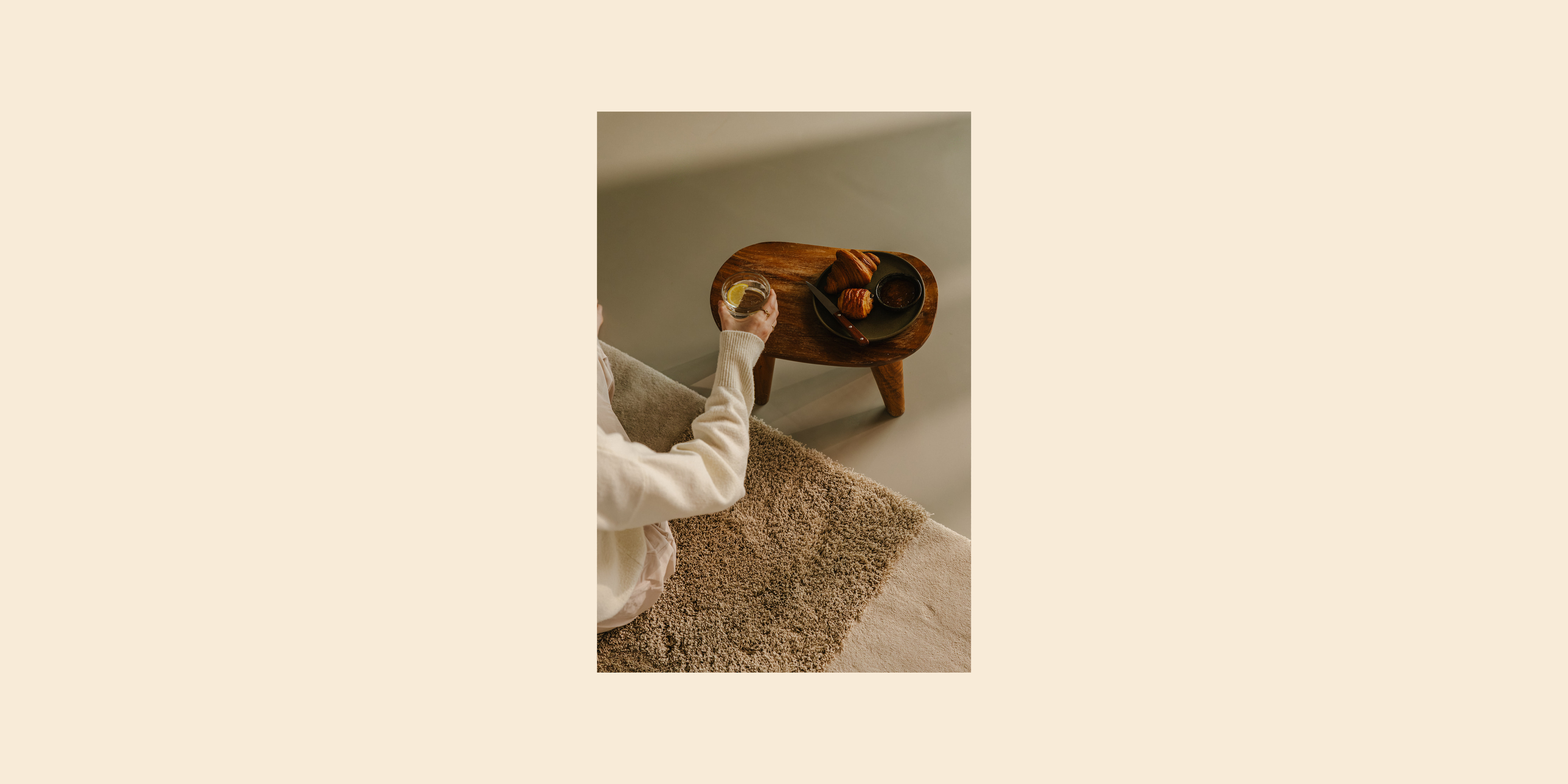 Rhythm modulair tapijt. Dune low & Desert high. Vrouw zit op het tapijt met een ontbijttafel. 