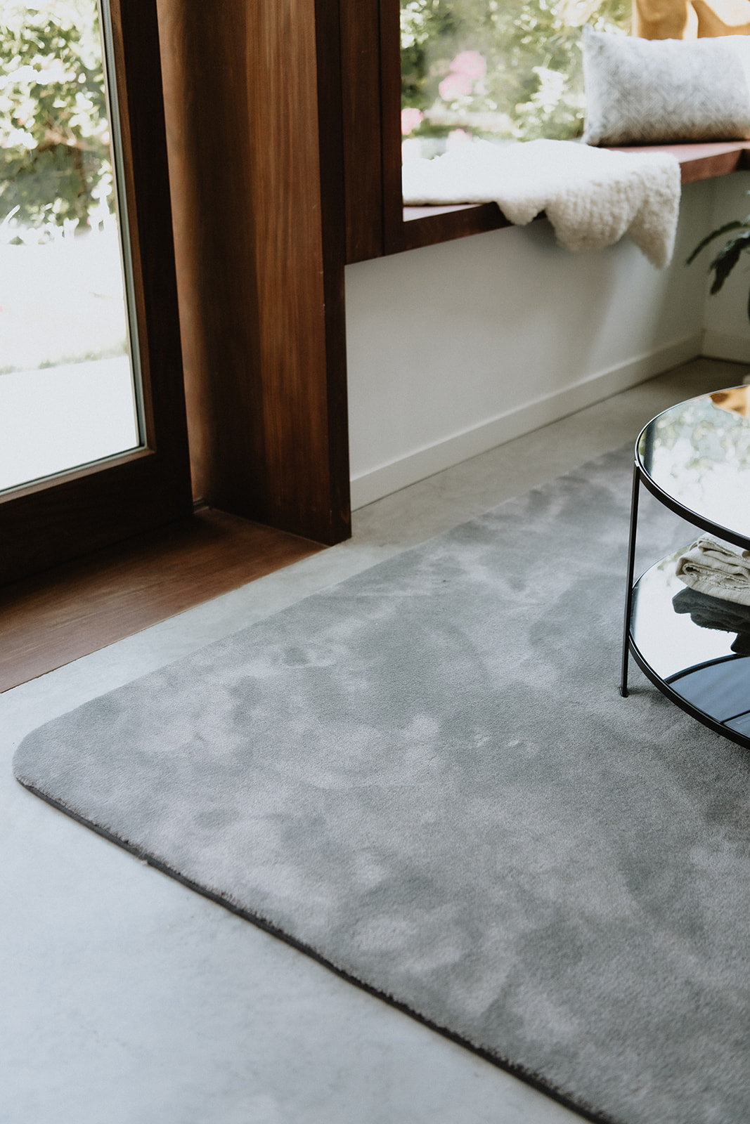 Interieurinspiratie van een circulair grijskleurig Rounded01. tapijt met stone kleurrand op een betonnen vloer.