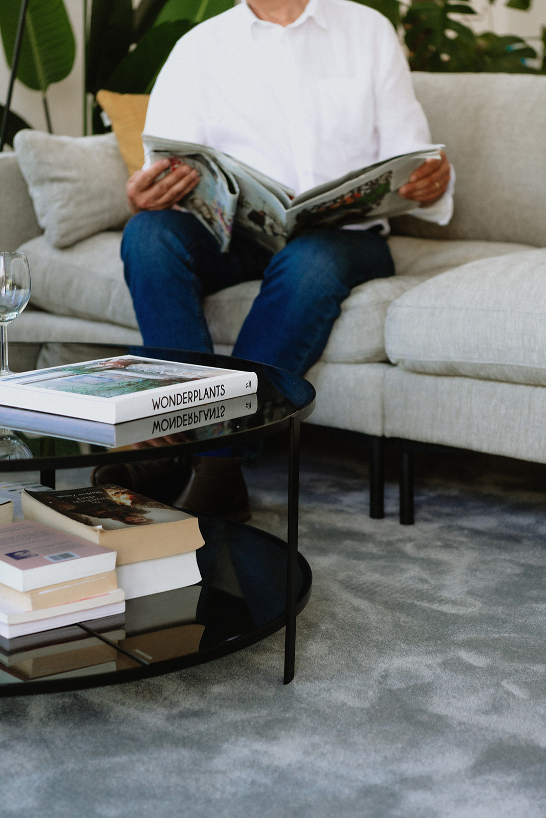 Interieur met bijzettafel, zetel en man die krant leest op een zacht duurzaam grijs vloerkleed.