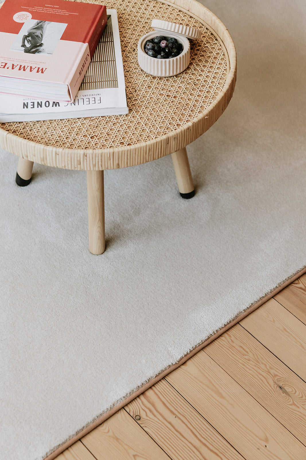 Close-up bijzettafel op beige-kleurig tapijt met blush kleurrand, op houten vloer.