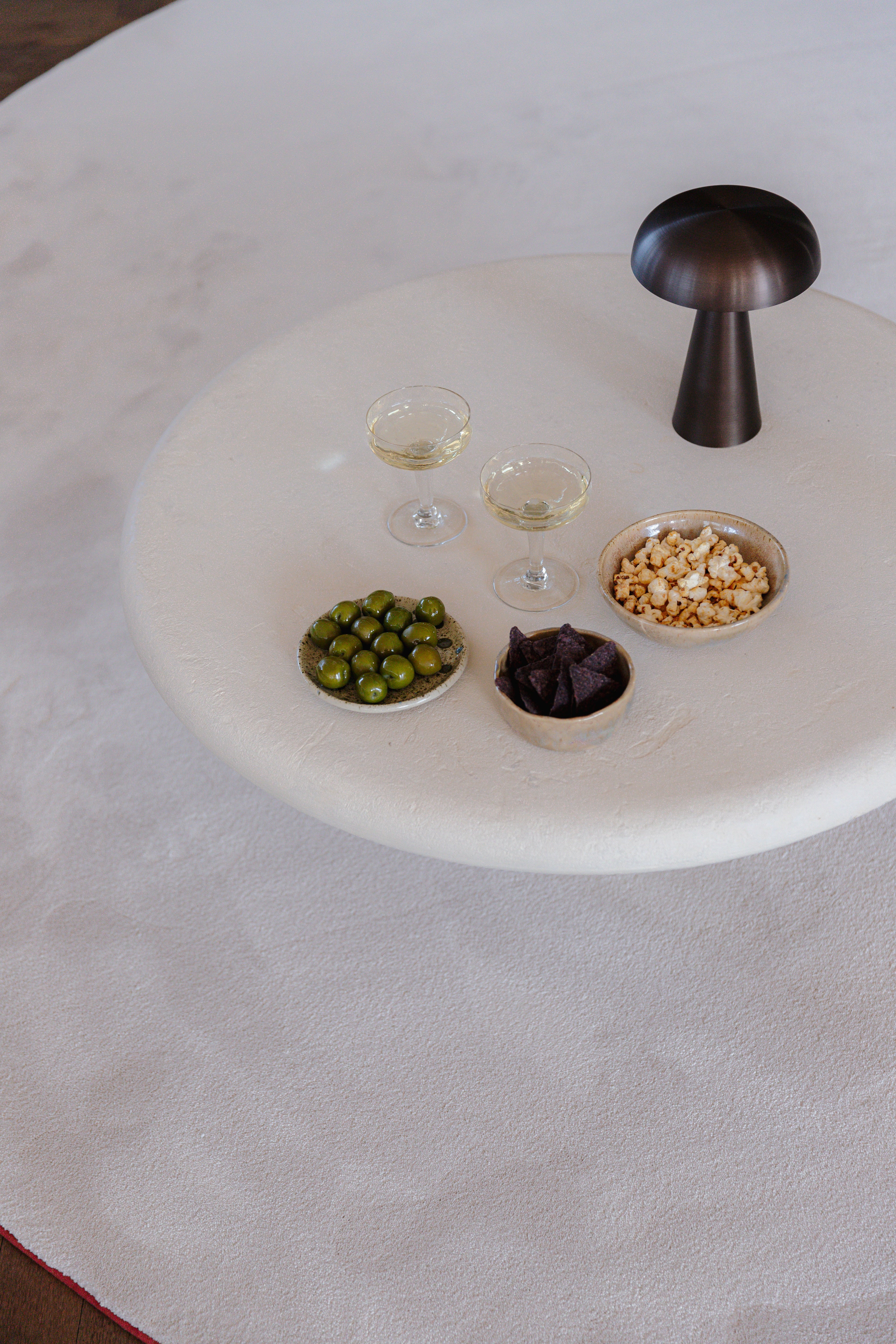 Apero tafel op rond ecologisch tapijt met witte tender kleur en rode terra rand.