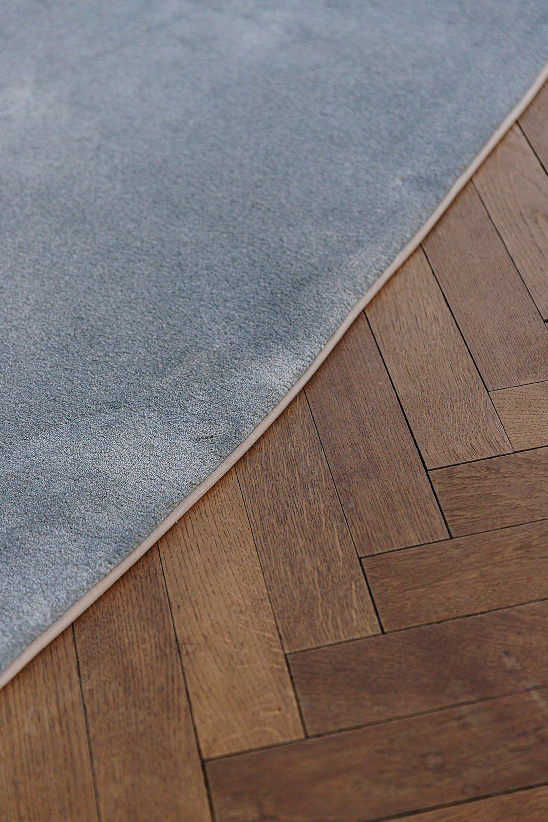 Detail gepersonaliseerde kleurrand rond vloerkleed op houten vloer.