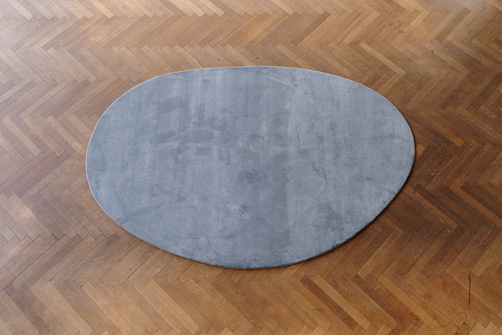 Bovenaanzicht pebble grijskleurig (stone) ecologisch tapijt op maat, op parket vloer.