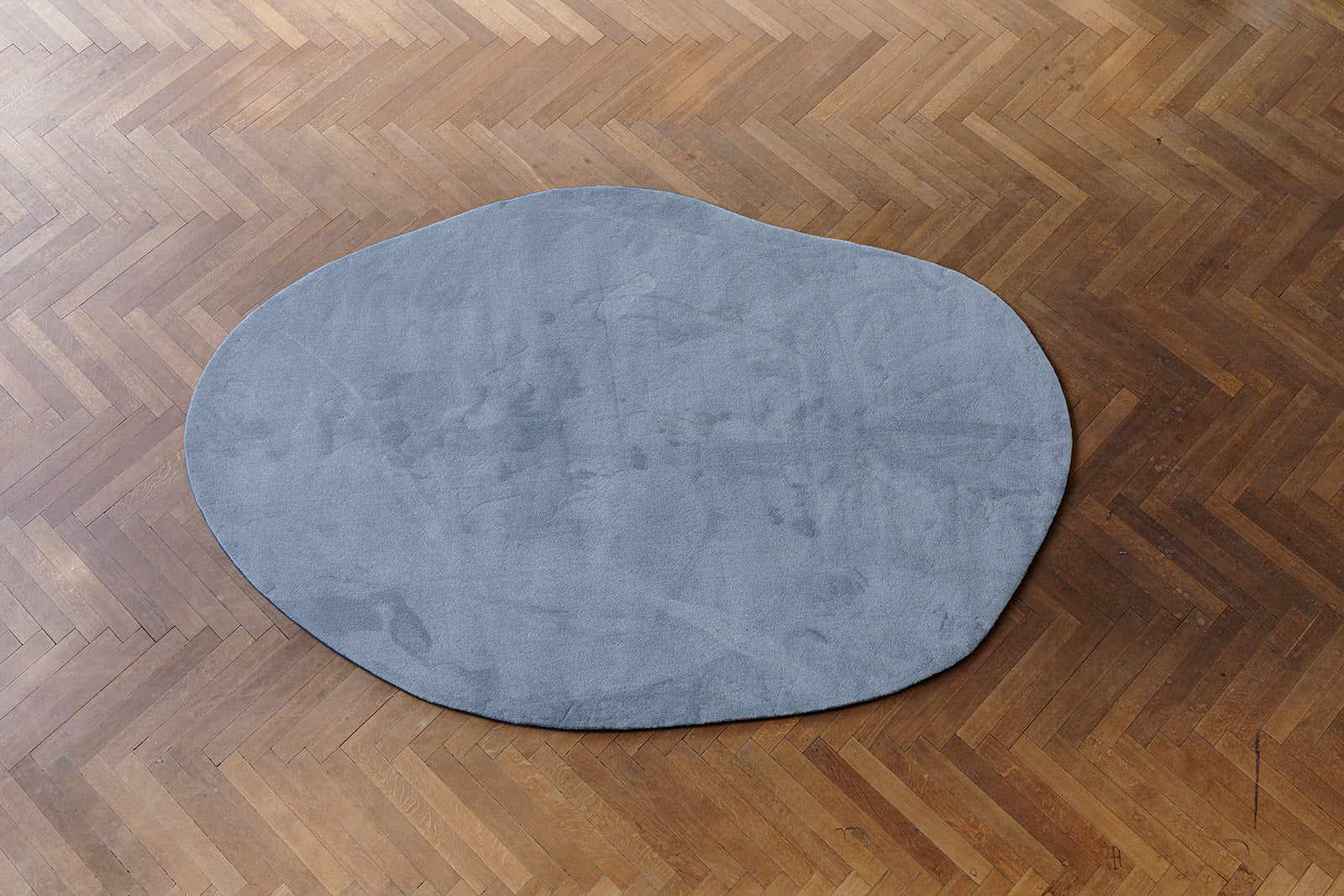 Bovenaanzicht pebble grijskleurig (stone) ecologisch tapijt op maat, op parket vloer.