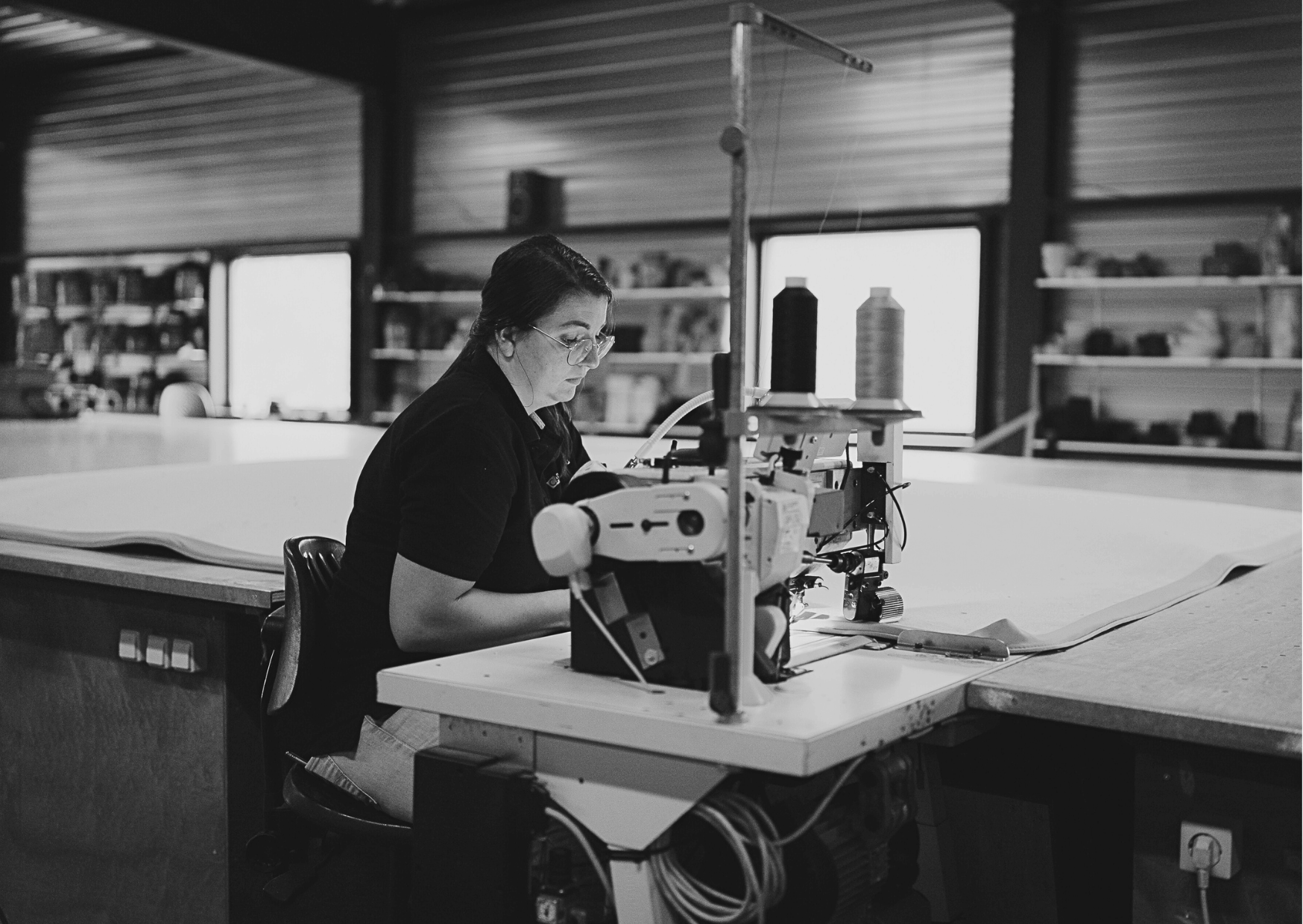 Lokale productie (België/Nederland) door medewerker en handgestikte rand van duurzaam tapijt aan machine.