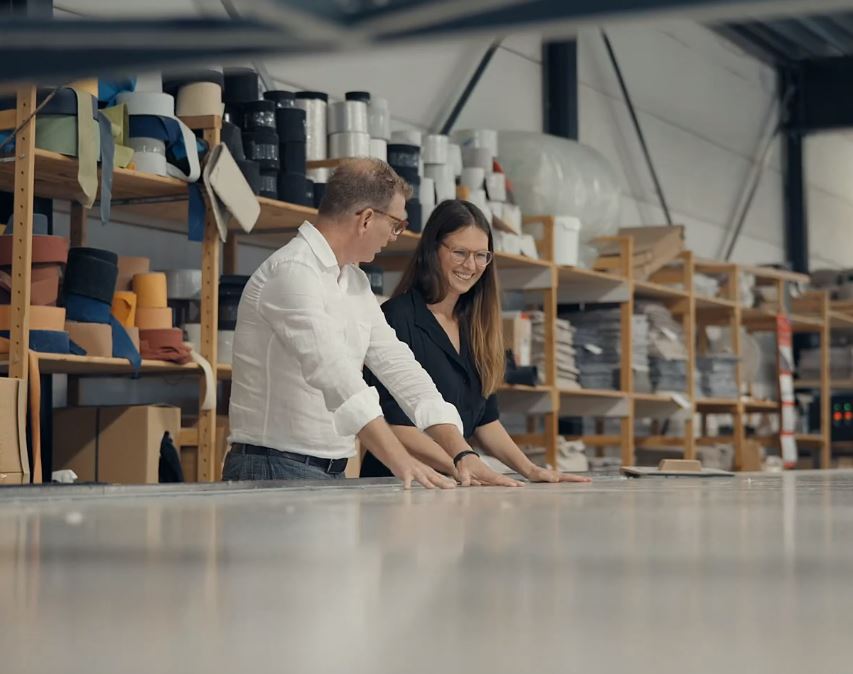 Jozefien Forton in lokaal atelier met werknemer voor duurzame productie van tapijten.